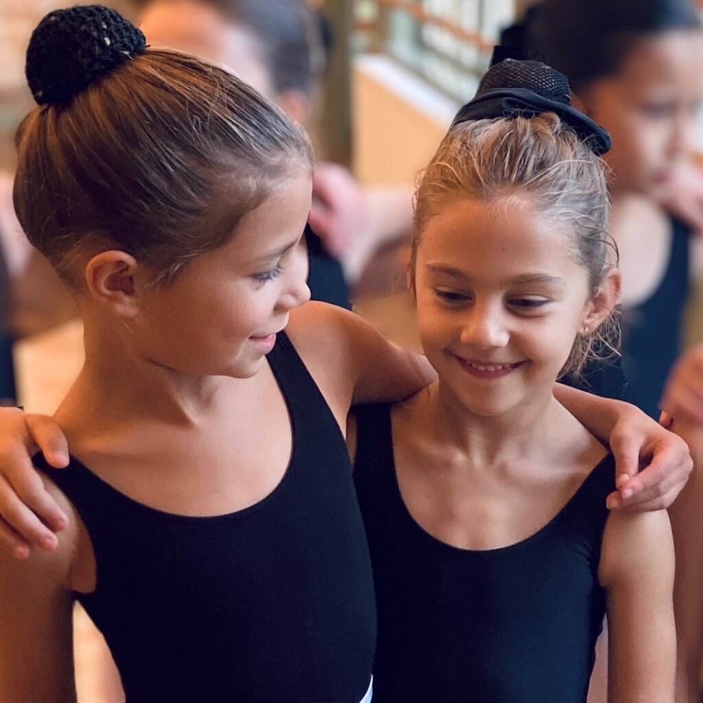 Twee kinderen met armen om elkaar heen, dikke vriendinnen samen in de balletles.